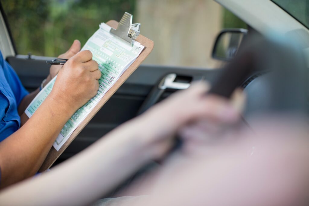 Close-up of inspector in car writing on test script